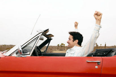 Man in car with hands raised